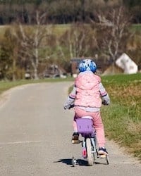 Girl Being Brave Riding Bike Training Wheels