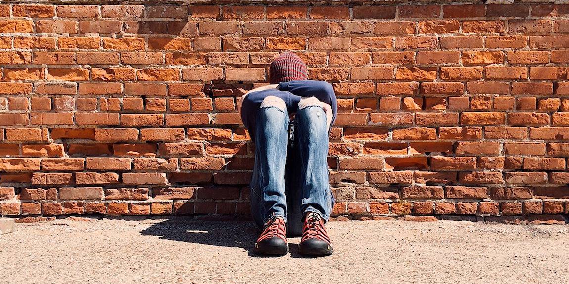 Sad Boy Sitting Against Wall